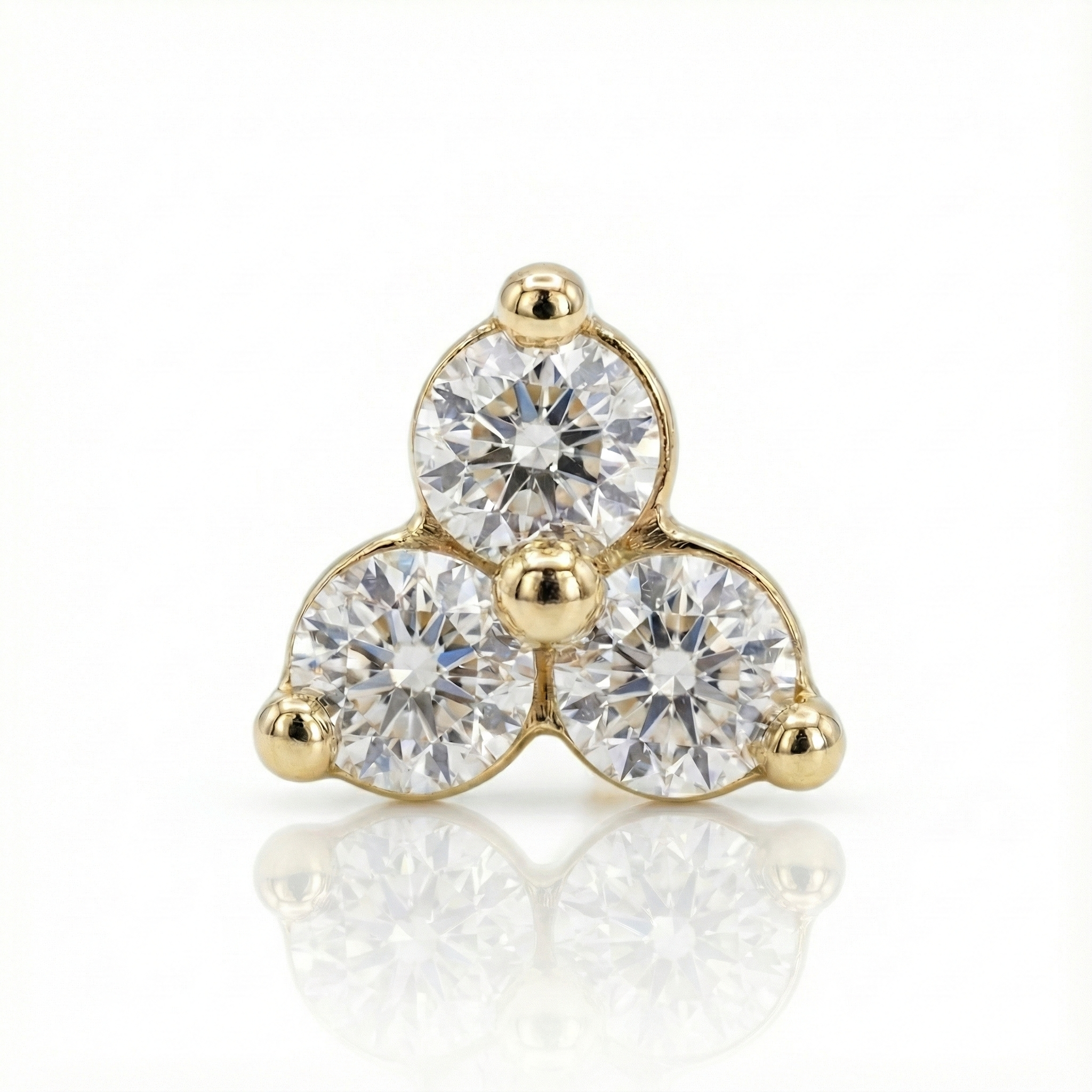 Gold earring with three clear gemstones on a white background