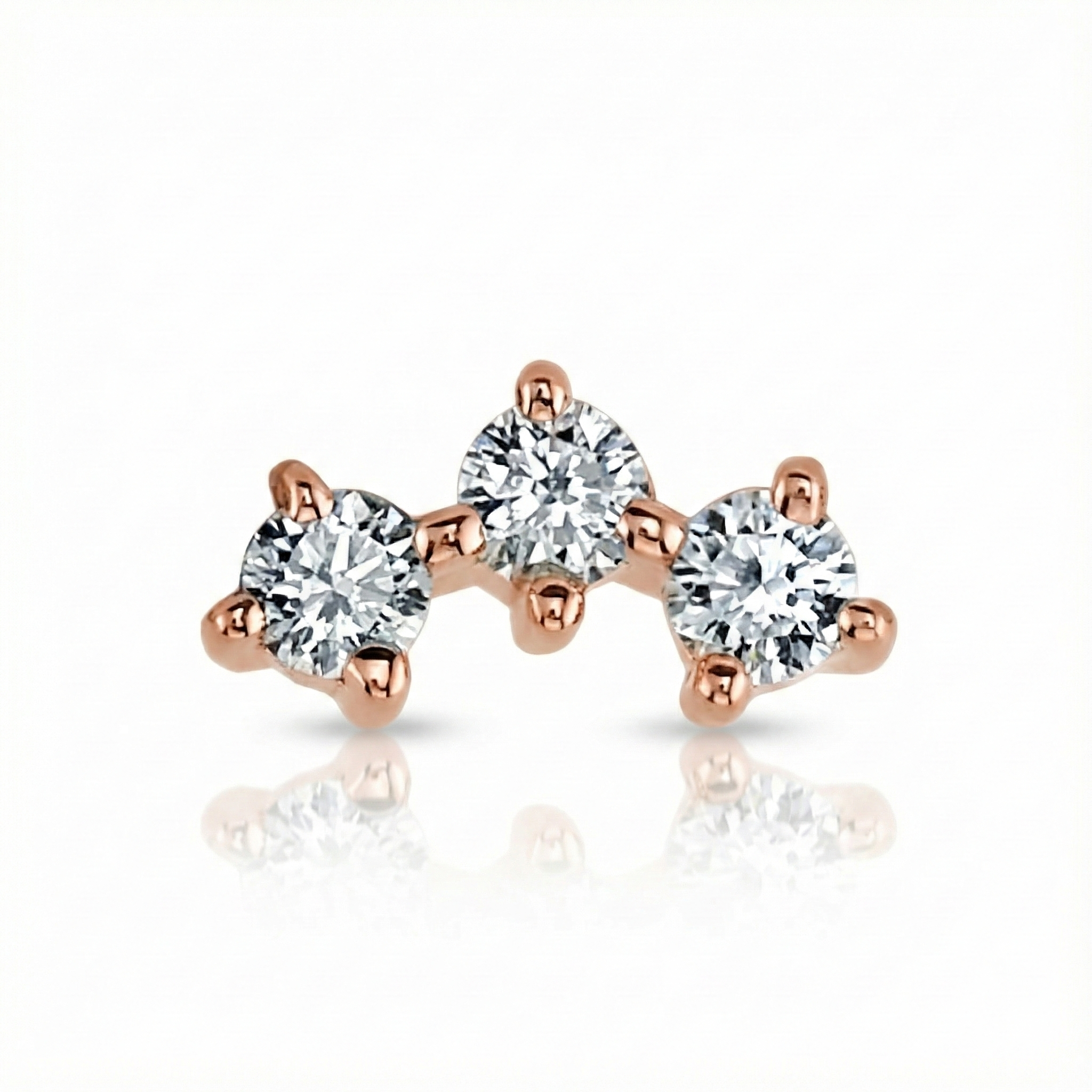 Rose gold earrings with three clear gemstones on a white background
