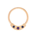 Gold ring with three purple gemstones on a white background