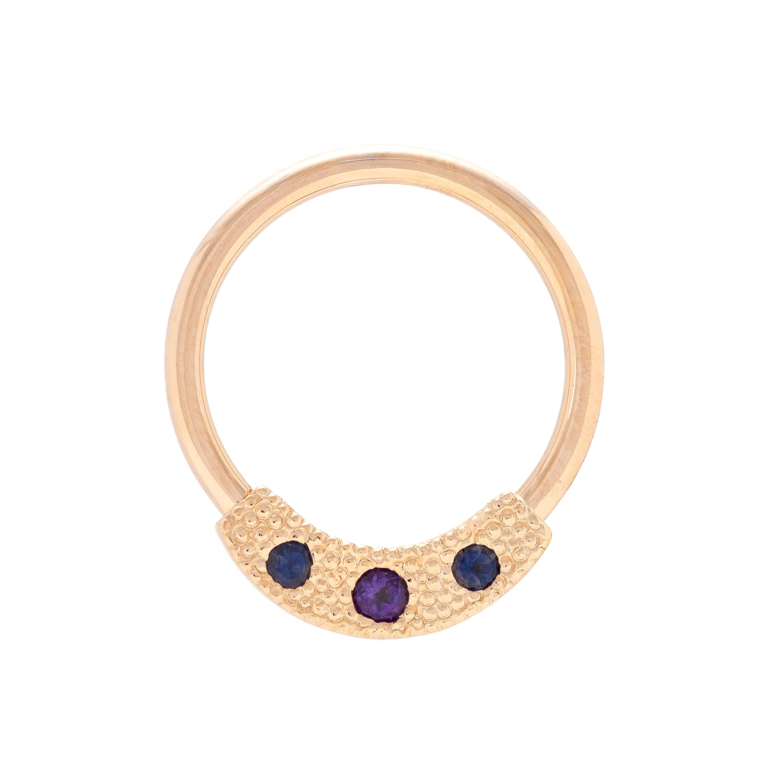 Gold ring with three purple gemstones on a white background