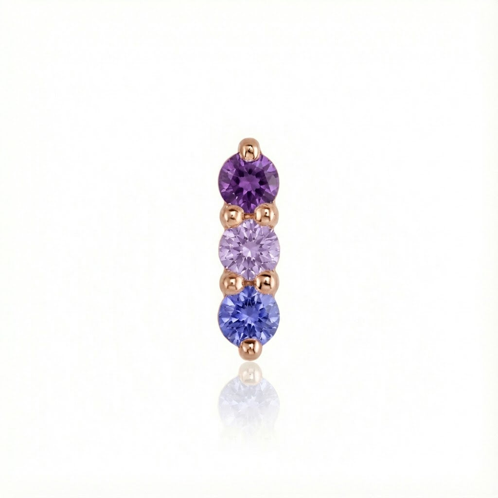 Gold earring with purple and blue gemstones on a white background