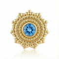 Gold charm with a blue gemstone on a white background